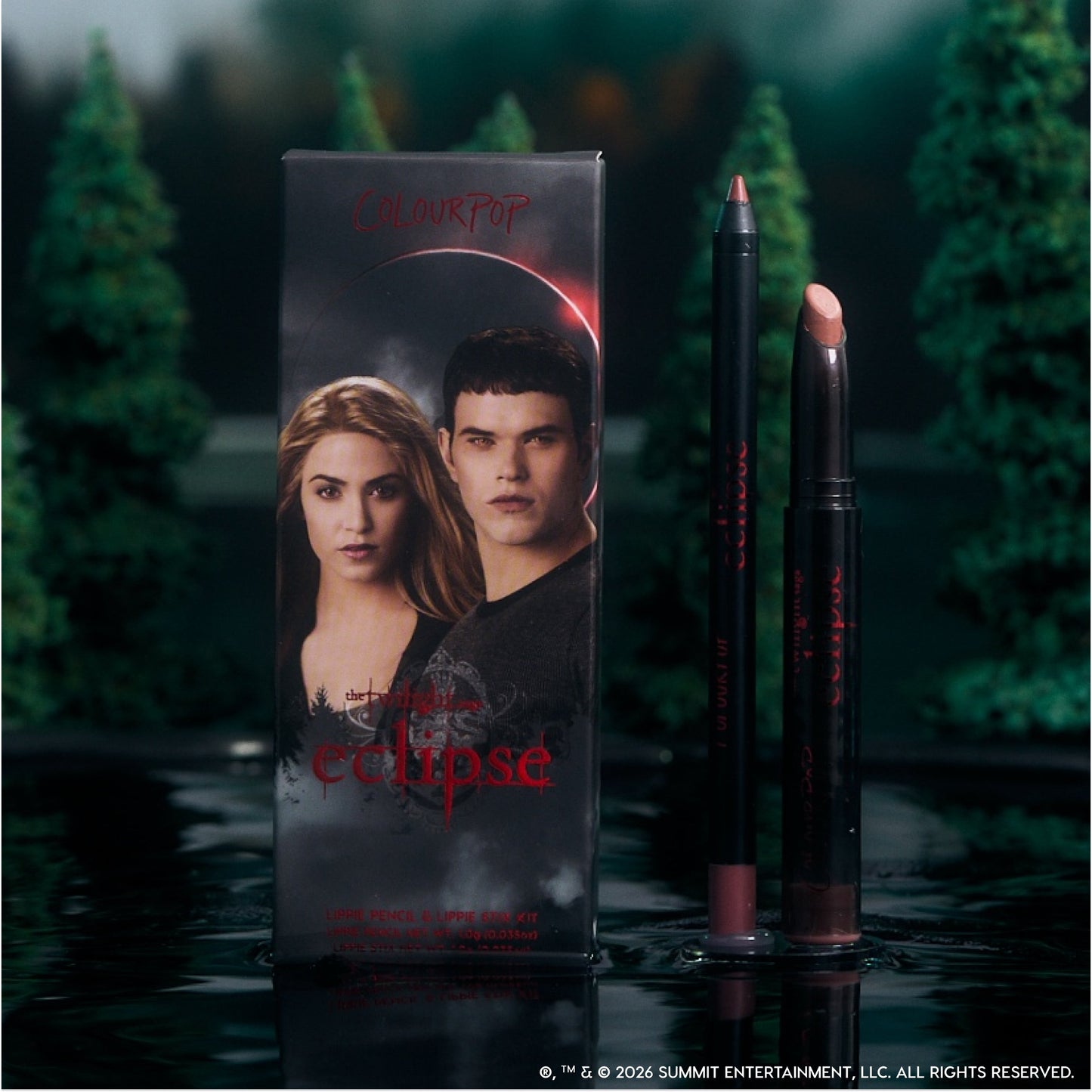 ColourPop Opposites Attract Lippie Stix and lip pencil from the Twilight Eclipse collection stand beside their character-adorned box on a reflective lake surface, surrounded by dark evergreen trees for a moody, cinematic makeup display.