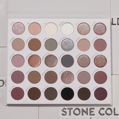 Stone Cold Fox ColourPop Shadow Palette lies open, displaying 30 cool-toned neutrals - taupes, mauves, grays, and browns - in matte, shimmer, and metallic finishes inside a white case on a light textured surface with the logo partly visible.