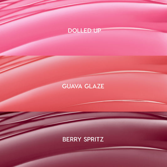 ColourPop So Juicy Plumping Gloss Balm with Peptides swatches showing She’s So Juicy shades: Dolled Up (bright pink), Guava Glaze (coral peach), and Berry Spritz (deep berry), displayed as glossy curved stripes in a close-up bundle layout.
