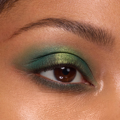 Eyelid wearing Just My Luck shades from the ColourPop Shadow Palette, blending emerald to lime metallic greens across the lid, with soft shimmer, defined lashes, and a groomed brow, illustrating bold pigment and seamless blend.