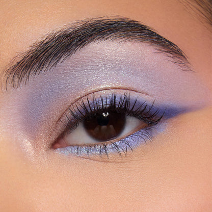 Shimmery lavender-to-blue winged eyeshadow accenting a brown eye, with an iridescent inner corner and lilac lower lash line, showcasing shades from the Disney Lilo and Stitch Collection ColourPop Full Collection Set in a close-up beauty shot.