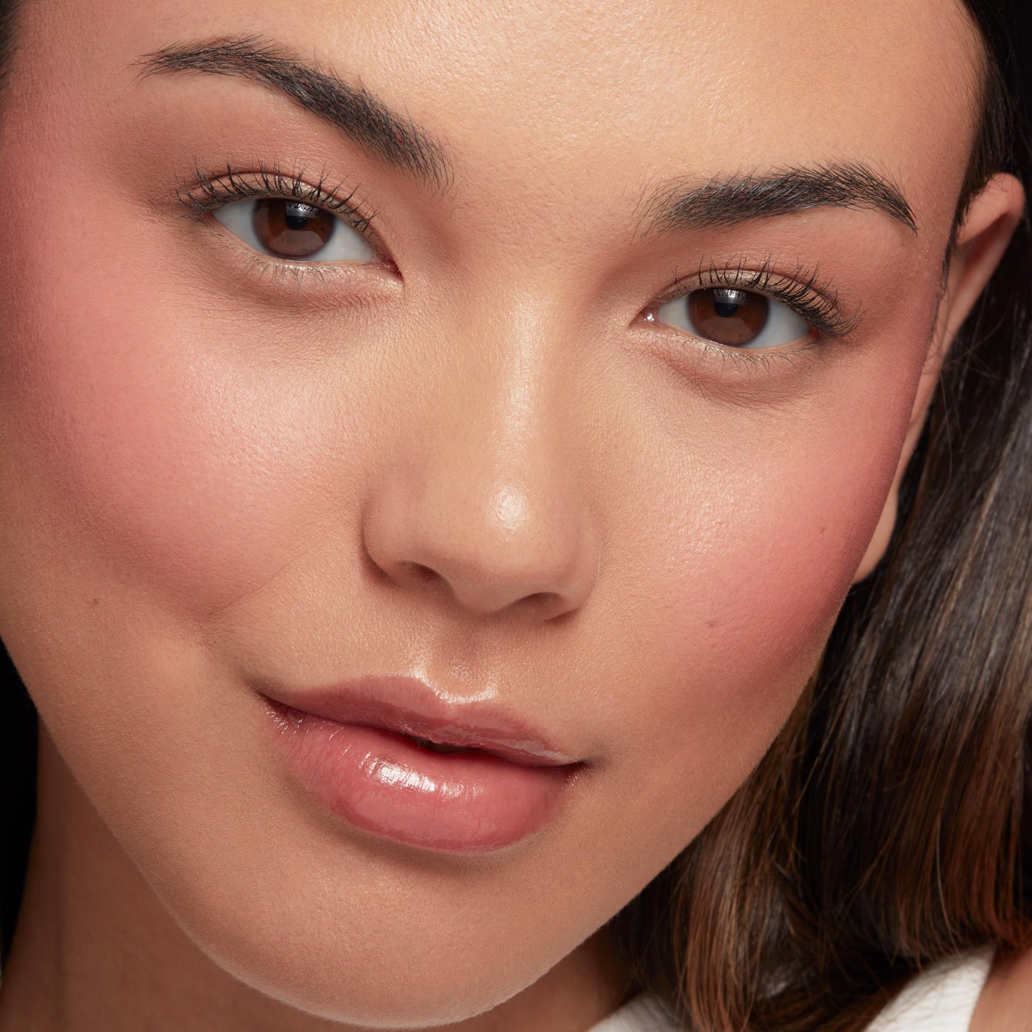 She’s Cute Liquid Blush adds a rosy-peach flush to the cheeks in a studio-lit close-up, while glossy lips enhanced with ColourPop So Juicy Plumping Glossy Lip Oil and natural lashes complete a fresh, dewy makeup look.