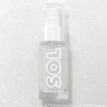 Like Diamonds pump bottle displaying iridescent micro-shimmer through frosted glass with bold white SOL logo, ColourPop SOL Shimmering Dry Oil, standing upright on a silver glitter backdrop that enhances the sparkle for a luminous body glow.