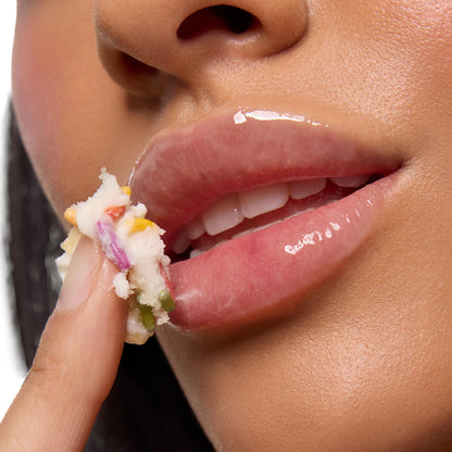 Glossy lips apply a creamy vanilla cake lip mask with colorful sprinkles using a fingertip in a close-up beauty shot, showcasing the hydrating shine of the Vanilla Dream Lip Care Kit, a ColourPop Lip Care Kit that smooths and nourishes for soft, supple lips.