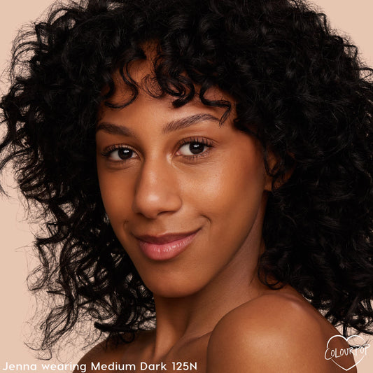 Model wearing ColourPop Pretty Fresh Creamy Concealer in Medium Dark 125 N (neutral undertone), showcasing smooth, natural coverage and a skin-like finish in a close-up against a soft beige background.