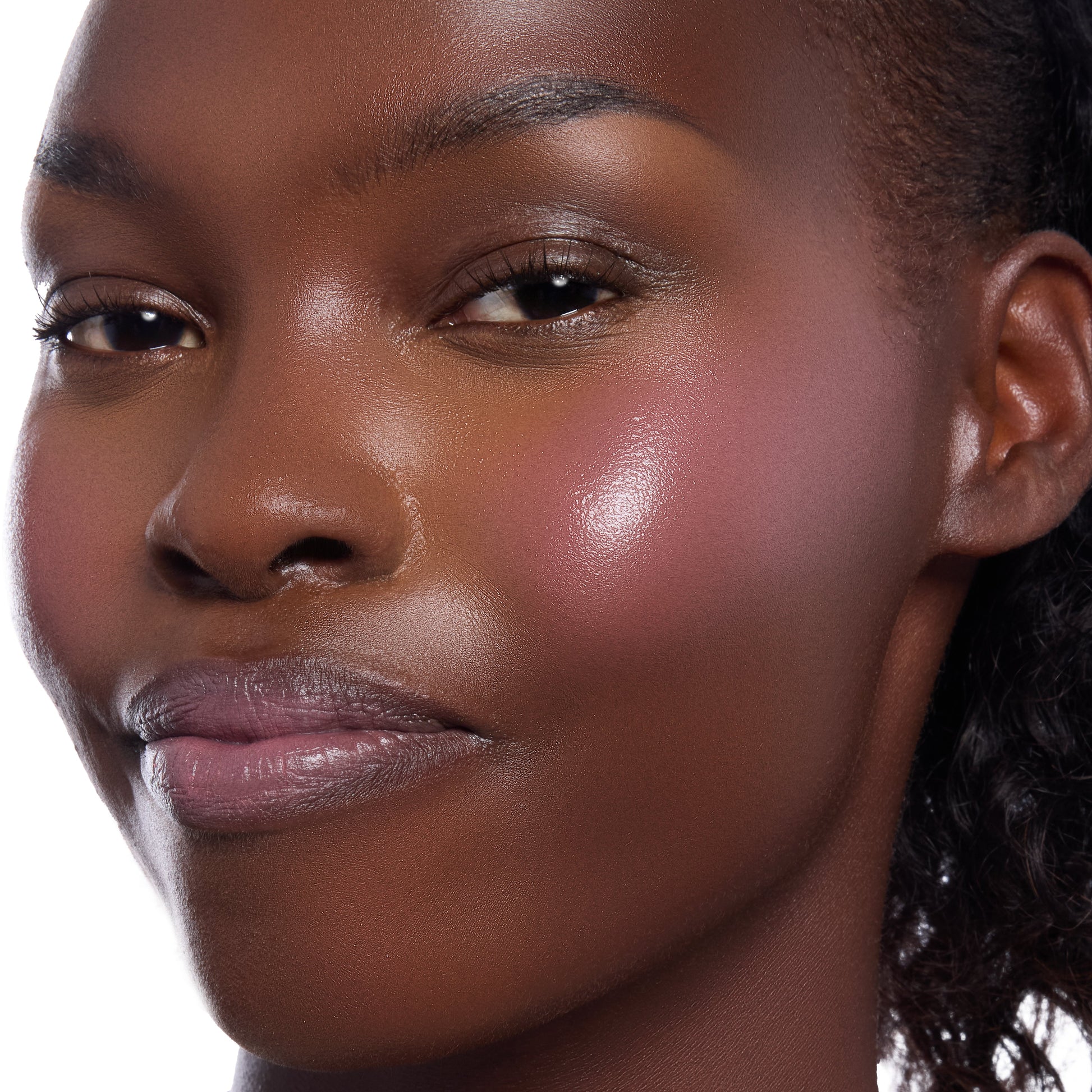 Model close-up wearing True Love’s Form ColourPop Lip and Cheek Balm, showing a rosy-plum flush and dewy sheen on the cheek with a soft tint on the lips, captured in crisp studio lighting against a clean white background.