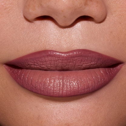 Close-up of full lips wearing ColourPop Opposites Attract Lippie Stix, showing a smooth, satin-matte mauve finish inspired by Twilight tones on medium skin, highlighting even coverage and creamy texture for everyday makeup looks.